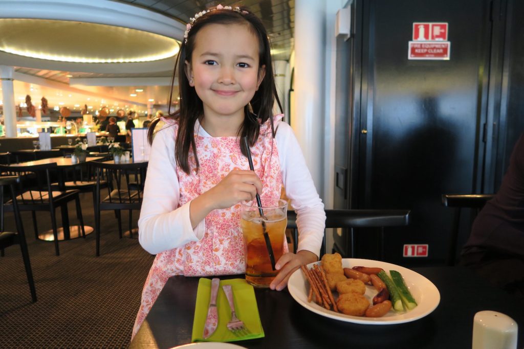 En superfornøyd jente gleder seg til å kose seg med middag om bord, med et stort glass eplejuice. Om bord på DFDS er alt så mye mer stas enn hjemme! Også maten! 